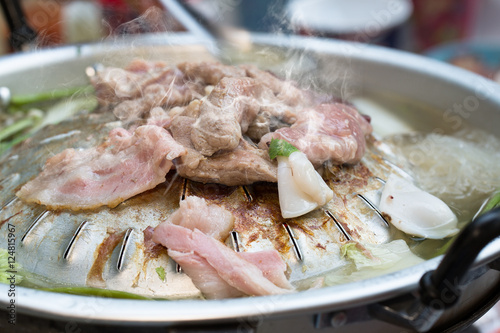 Grilling sliced pork and meat with ingredients on hot pan asian
