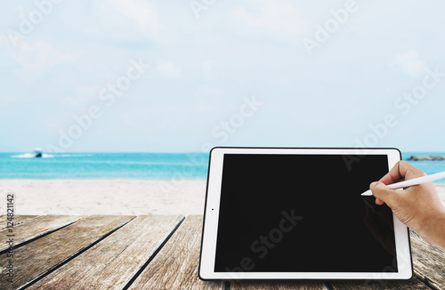 The beach holidays, Hand writing on digital tablet. with wooden terrace at tropical beach. copy space on screen