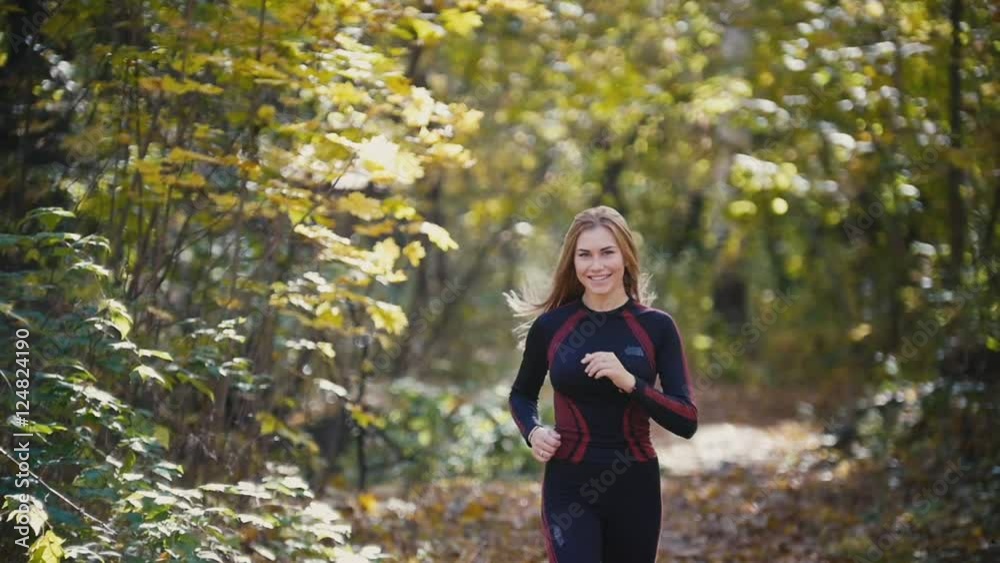 Young active female athlete exercising outdoor autumn park. Girl smiling, hair waving, Healthy women, slow-motion Young active female athlete exercising outdoor autumn park. Girl smiling, hair waving, Healthy women, slow-motion