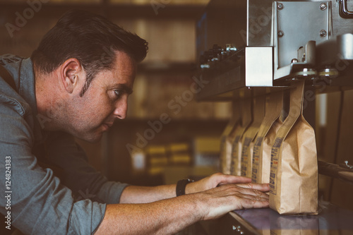 Worker looking at line of packed coffee beans