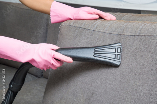 Professionally nozzle releasing sofa pillow from dust. Early spring cleaning or regular clean up. Upholstered furniture.