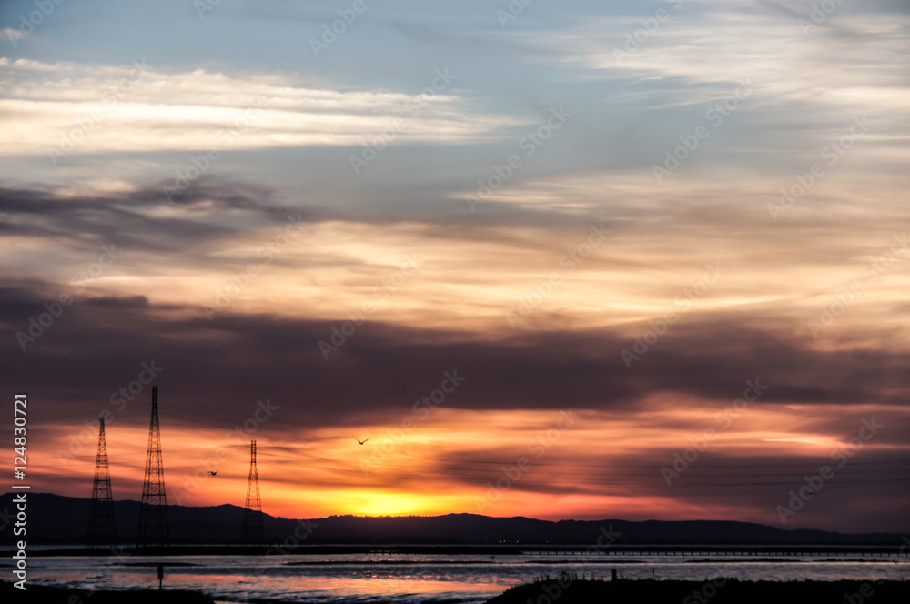 Ominous Sunset Skies over Alviso marina County Park, San Francisco Bay Area, California, USA. Intensive colored Sunset of hills and power transmission towers in the bay area. Ominous Sunset Skies over Alviso marina County Park, San Francisco Bay Area, California, USA. Intensive colored Sunset of hills and power transmission towers in the bay area.