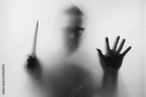 Horror Murderer. Dangerous man behind the frosted glass with a k