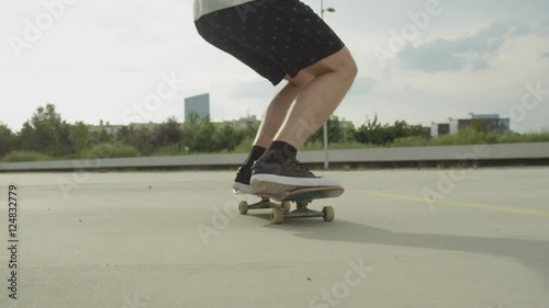 SLOW MOTION CLOSE UP: Skateboarder skating and jumping ollie tricks photo