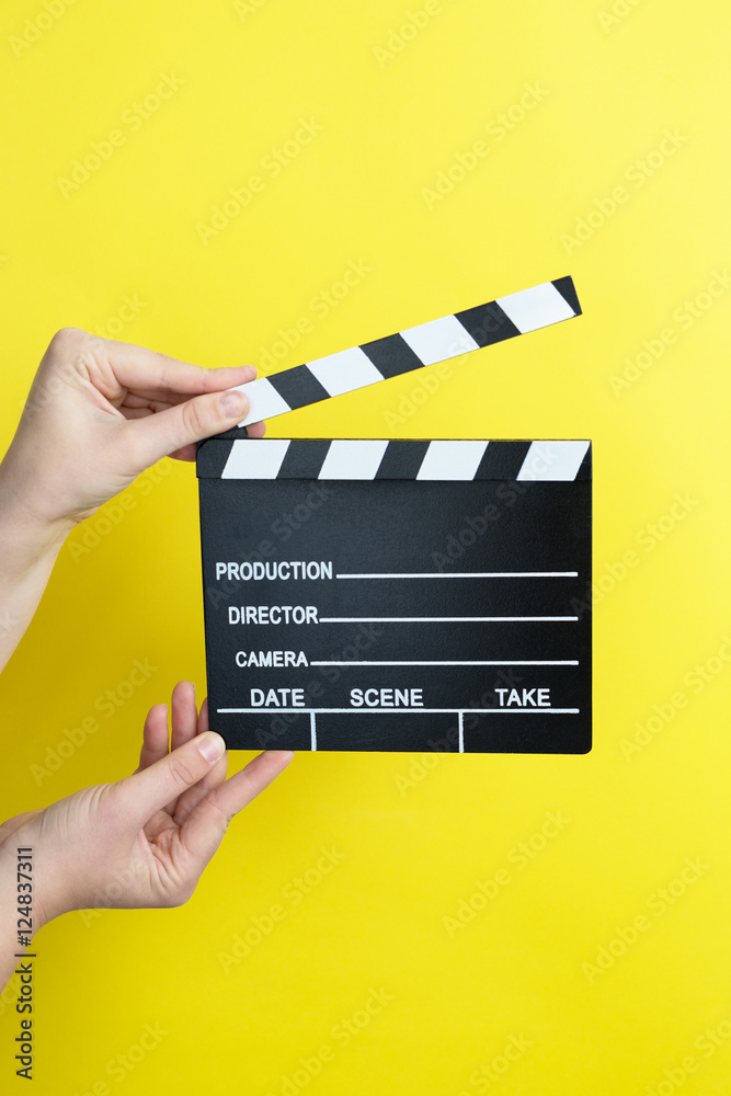 woman holding movie clapper on yellow background, cinema concept