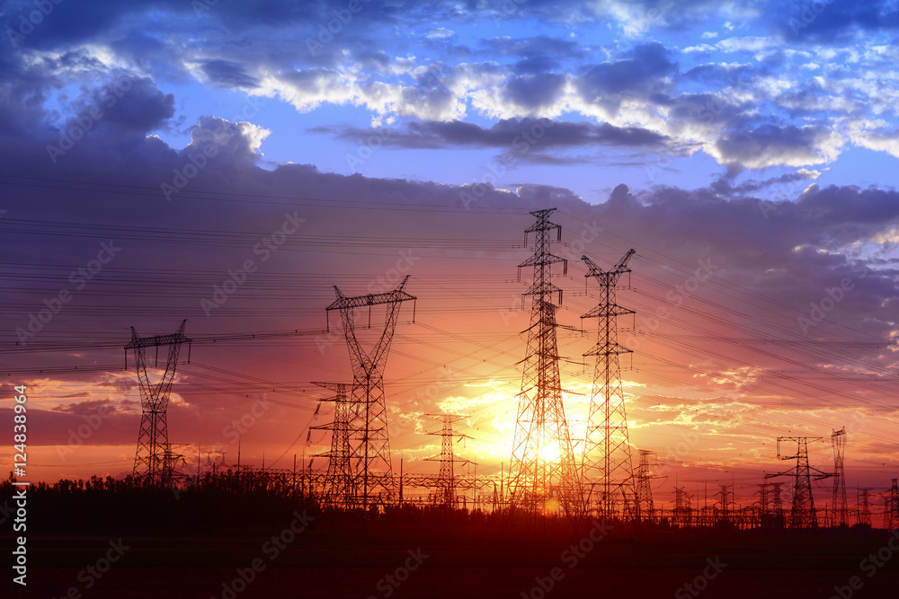 Fototapeta premium Many high voltage towers under the sunset