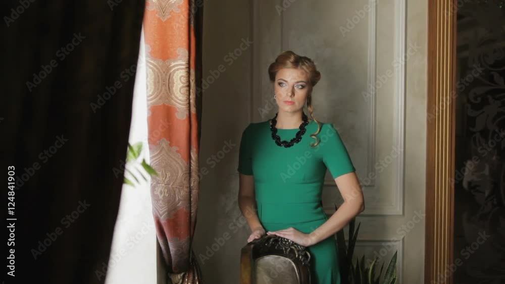 Woman posing next to the window. An attractive woman in a green dress ...