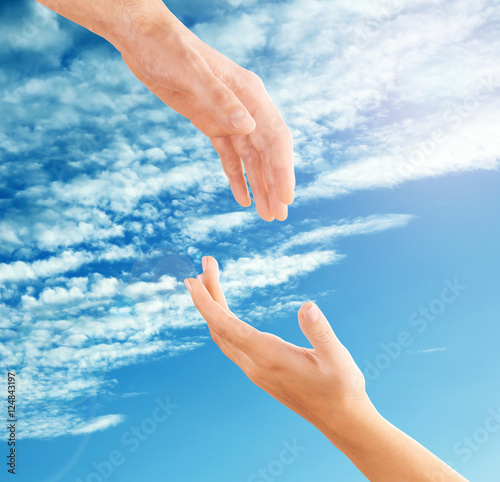 Female and male hands reaching to each other on sky background. Help and care concept. © Africa Studio