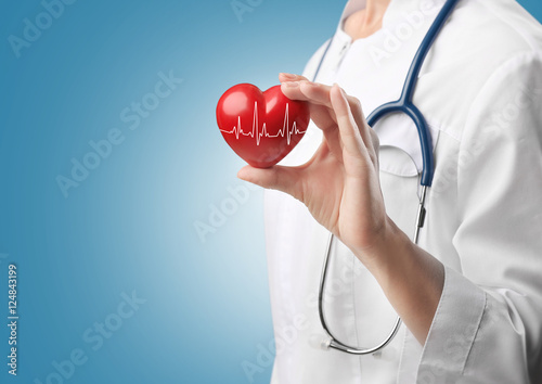 Fototapeta Cardiologist holding red heart with electrocardiogram