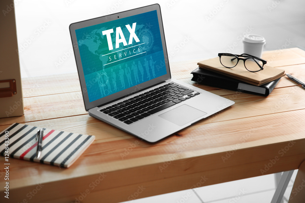 Modern workplace with laptop. Interface of TAX SERVICE website on screen. Online tax report concept. Modern workplace with laptop. Interface of TAX SERVICE website on screen. Online tax report concept.