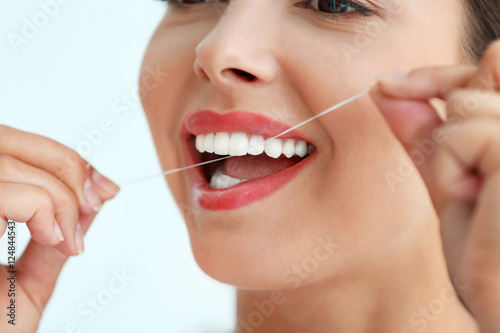 Young woman cleaning teeth with dental floss, close up
