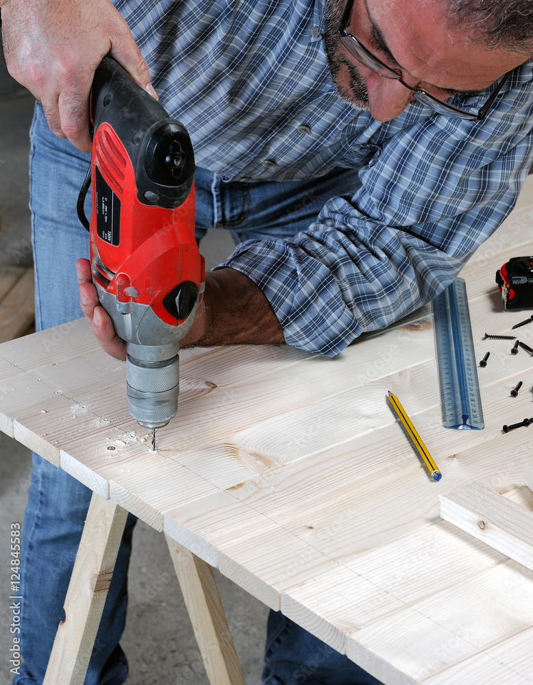 Adult artisan drill holes with a wooden panel to achieve an artifact. Adult artisan drill holes with a wooden panel to achieve an artifact.