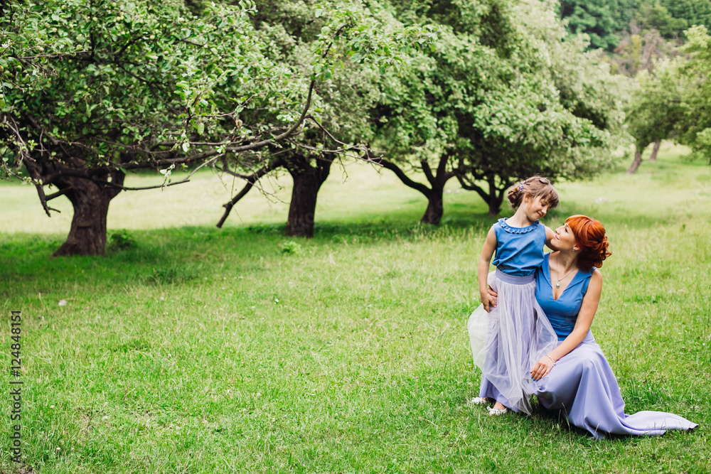 beautiful mother and daughter standing on green grass