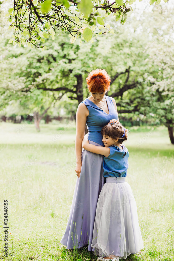 beautiful mother and daughter standing in the green garden beautiful mother and daughter standing in the green garden