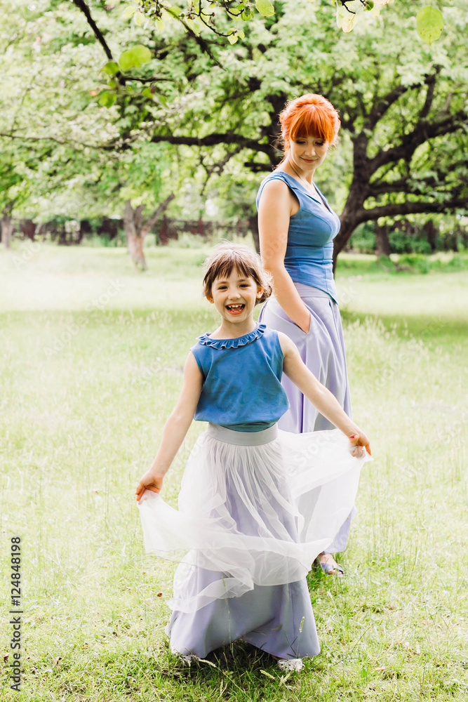 Fototapeta premium beautiful mother and daughter standing in the green garden