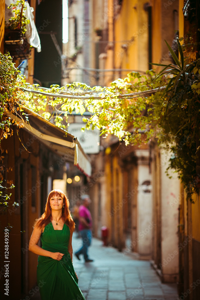 Woman with red hair walks in green dress around the city