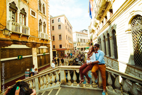 Man and woman sit hugging on the bridge in Venice