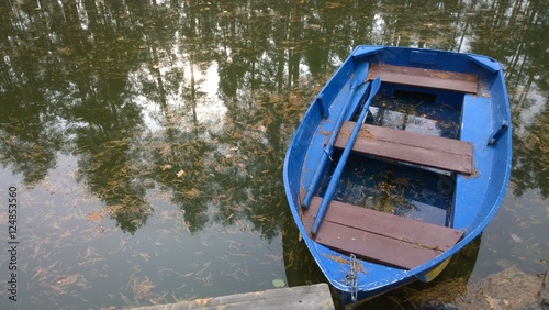 лодка на озере с отражением деревьев в воде