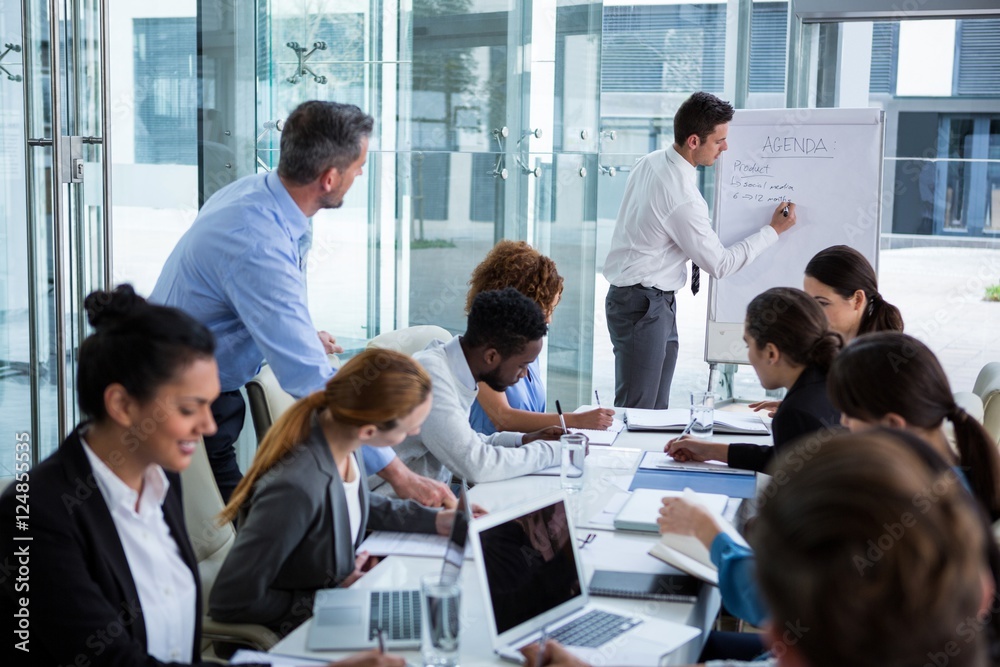 Businessman discussing on white board with coworkers Businessman discussing on white board with coworkers