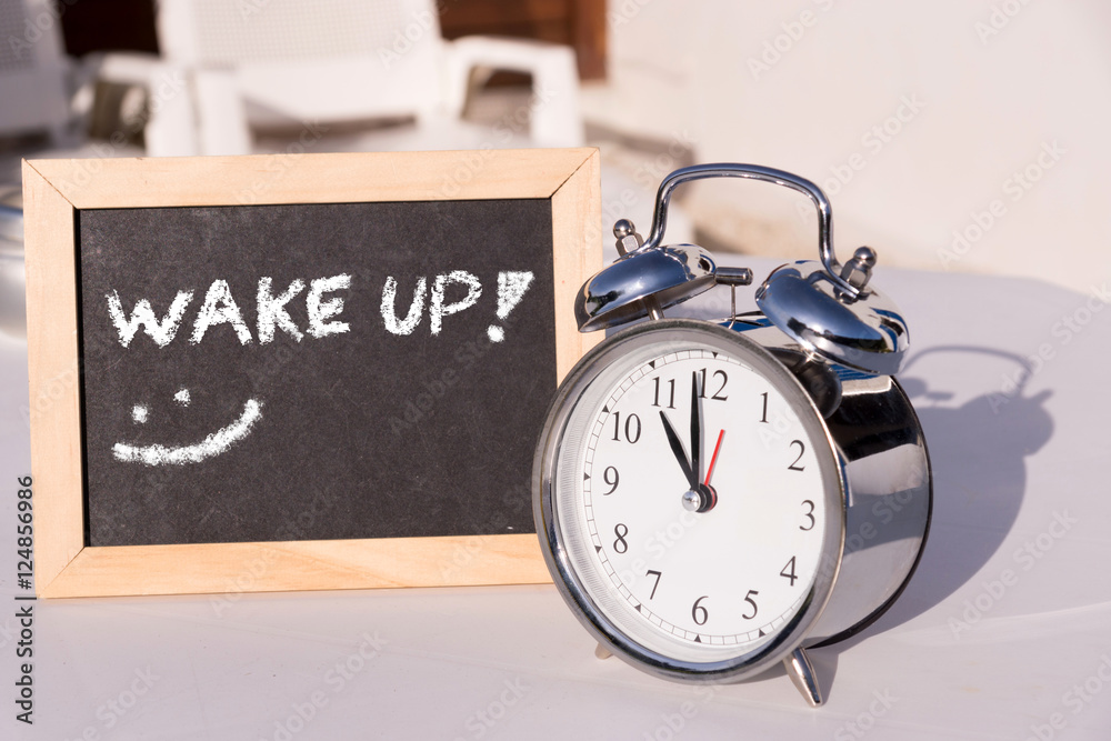 Ein Wecker und eine Tafel mit dem Wort Wake Up Ein Wecker und eine Tafel mit dem Wort Wake Up