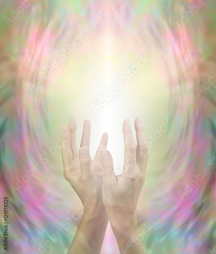 Beaming Beautiful Healing Energy - female hands held in gentlly cupped upright position with a stream of light streaming up on a golden pink and green background 
