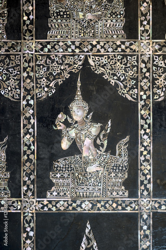 Antique Asian mother of pearl design featuring Thai dancer on black ebony background in a Buddhist temple in Bangkok, Thailand