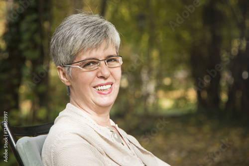 Close up portrait of lovely middle aged woman in the autumn park