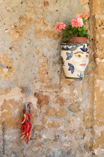 Textured wall with beautiful Sicilian ceramics in the form of hot peppers and pot-head photo