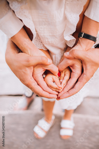 Obraz na płótnie A family of hands form a heart - father on the outside, then mother's hands and infant baby hands in the middle. w salonie