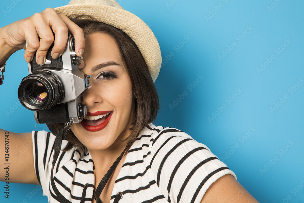 Fashion young girl makes the photo with old camera. Blue backgro Fashion young girl makes the photo with old camera. Blue backgro