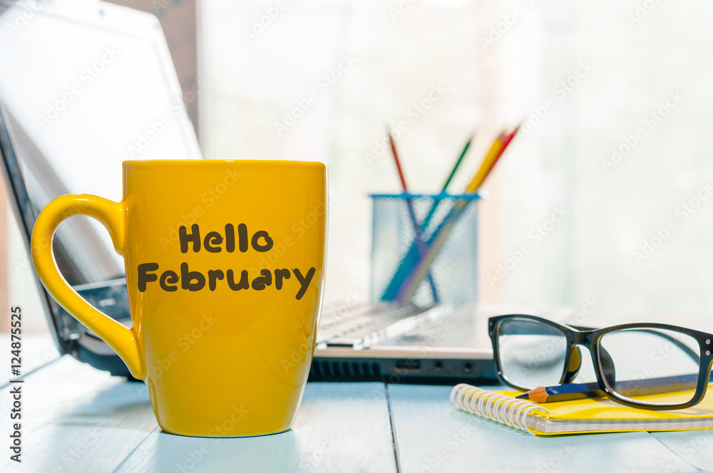 Hello February written on yellow coffee cup at business office background with empty space. Winter time - obrazy, fototapety, plakaty 