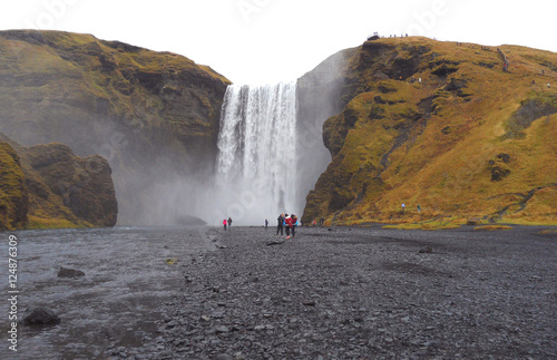 People admiring Skogafoss Waterfall on a cold autumn day, South Iceland