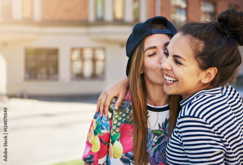 Fototapeta premium Affectionate young woman kissing her friend