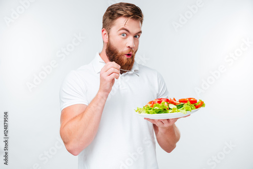 Happy excited bearded man holding plate with fresh sala a,