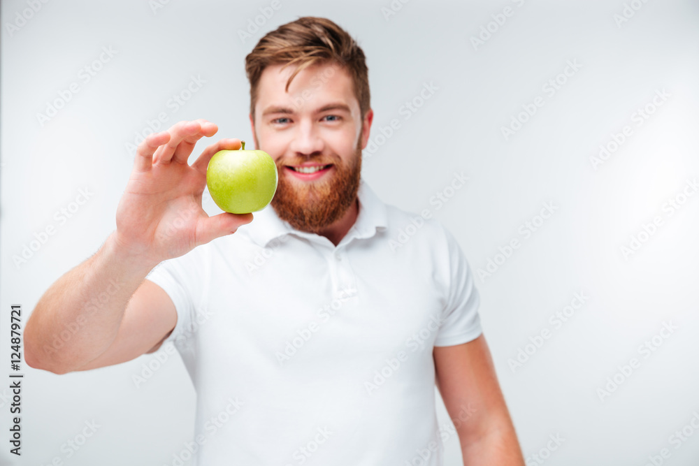 Casual bearded man holding green apple and looking at camera Casual bearded man holding green apple and looking at camera