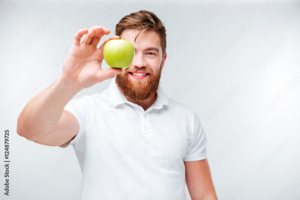 Casual bearded man showing green apple and looking at camera Casual bearded man showing green apple and looking at camera