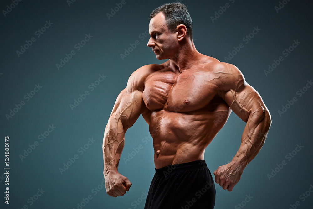 torso of attractive male body builder on gray background.