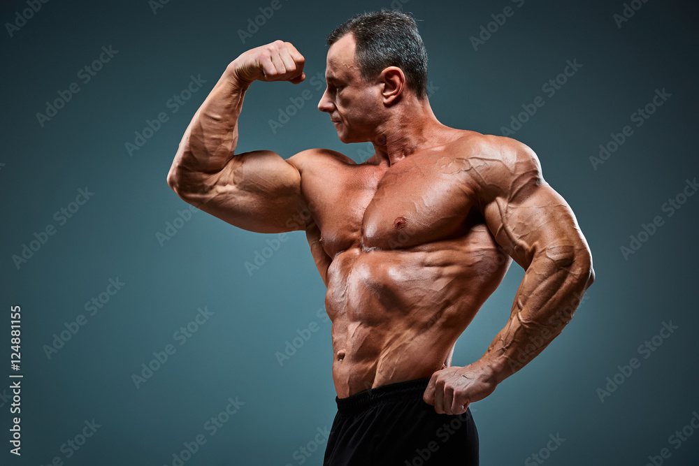 torso of attractive male body builder on gray background.