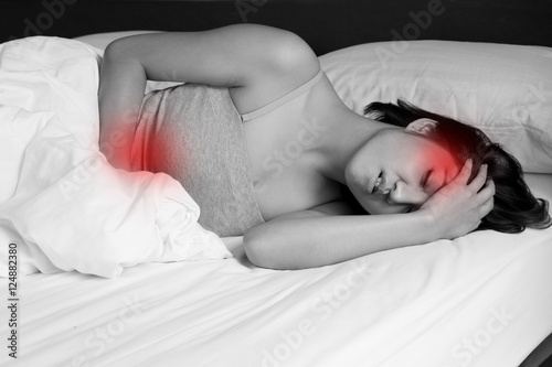 sick woman on bed concept of stomachache, menstrual cramp, heada