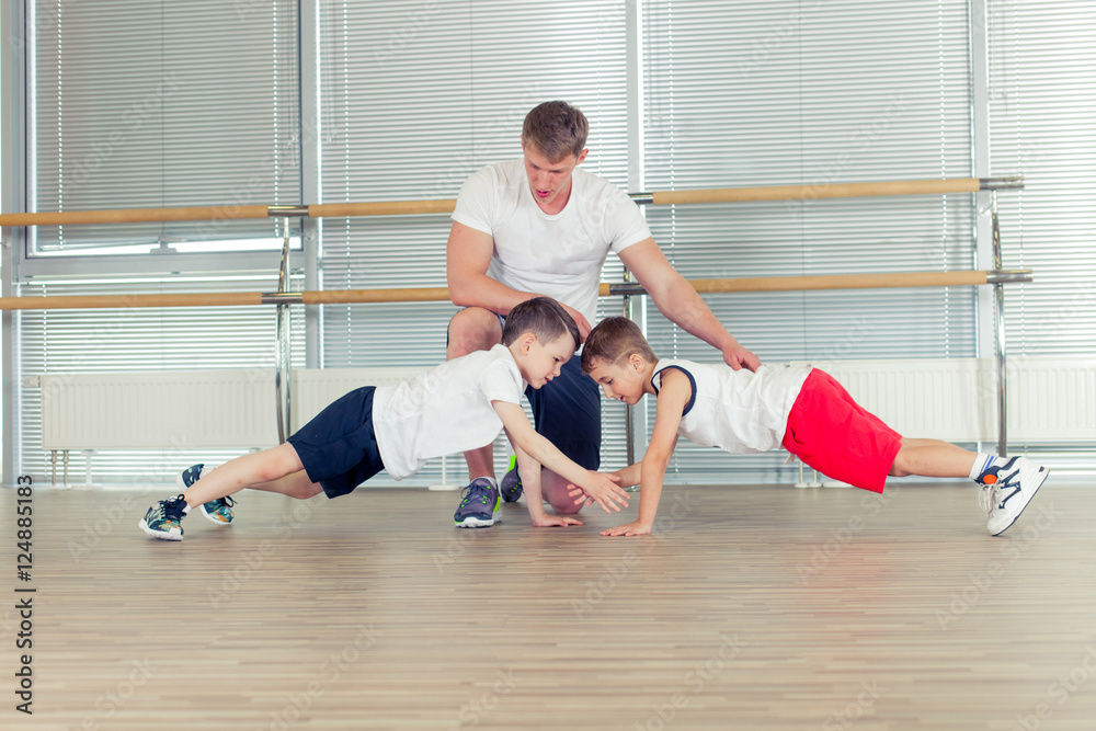 Group of children doing kids gymnastics in gym with nursery teac Group of children doing kids gymnastics in gym with nursery teac