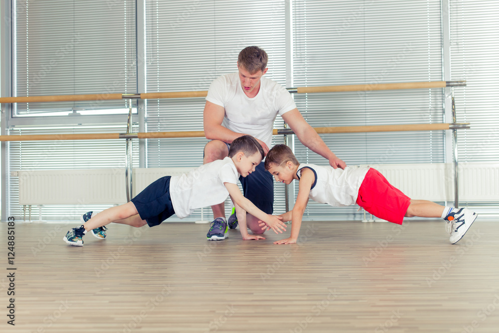 Group of children doing kids gymnastics in gym with nursery teac