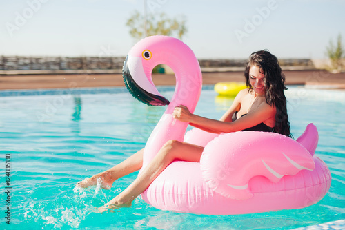 girl sits on inflatable mattress flamingos in the pool © sibstock