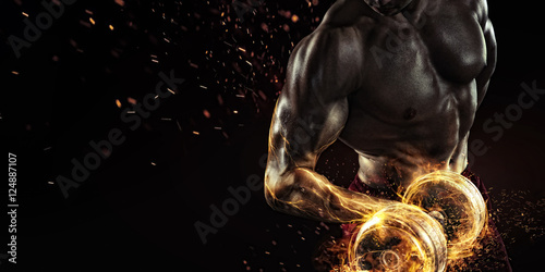 Sports background. Power athletic guy bodybuilder , execute exercise with dumbbells, in dark gym. Fire and energy