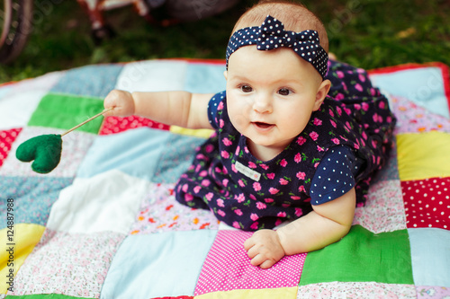 Delightful little girl holds a stick with green heart while lyin photo