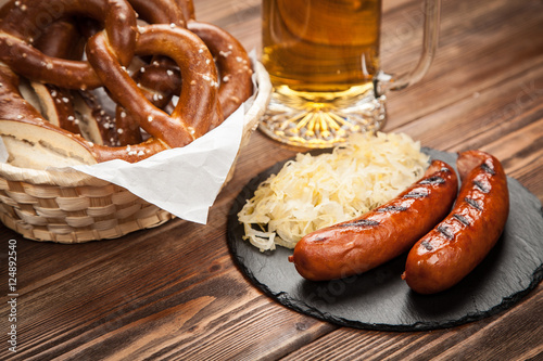 Pretzels, bratwurst and sauerkraut on wooden table