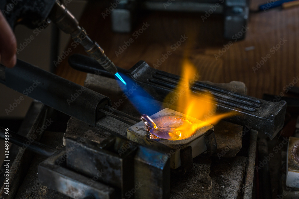 Melting a Silver Ingot to liquid state in crucible with blowtorch; Goldsmith Workshop; Close-up