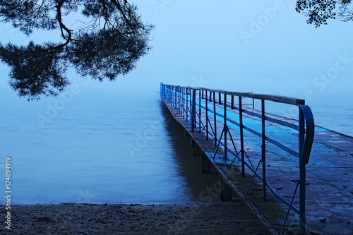 Fog in the morning by the lake. Old metal pier photo