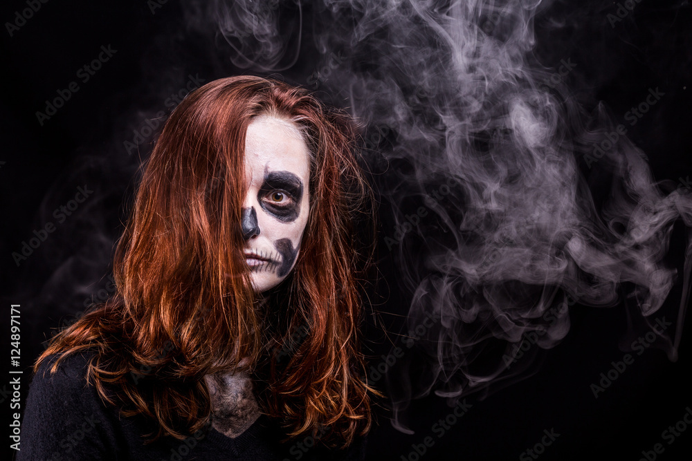 une jeune femme maquillée en squelette sur fond noir avec de la fumée