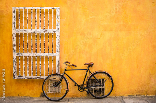 Classic bicycle against a yellow wall photo