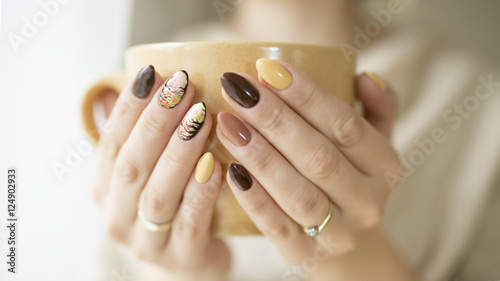 hands of autumn nails holding a cup of hot tea